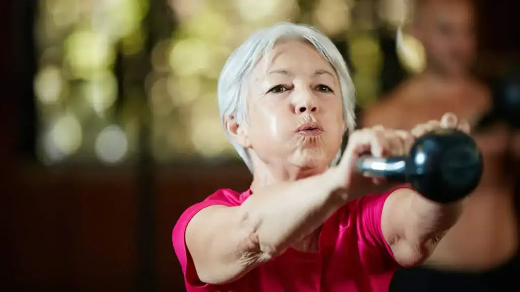 Older woman doing weight training  East Sussex to help her strength and longevity 