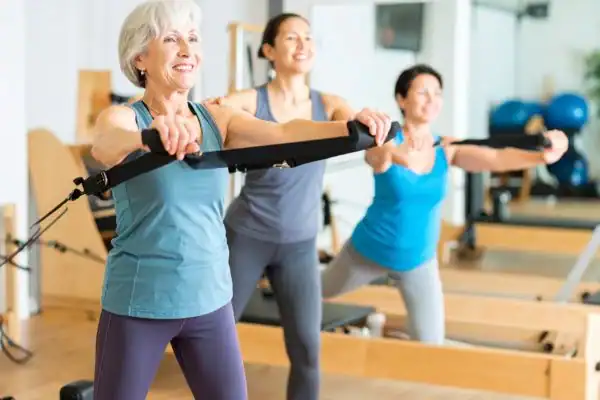 Toning Arms After 60: Empowering Womens Fitness Through Effective Weight Training 2 older woman doing weight training East Sussex and resistance in the gym to tone upper arms