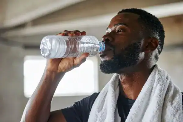 Image of man drinking water to improve hydration  East Sussex after work out.